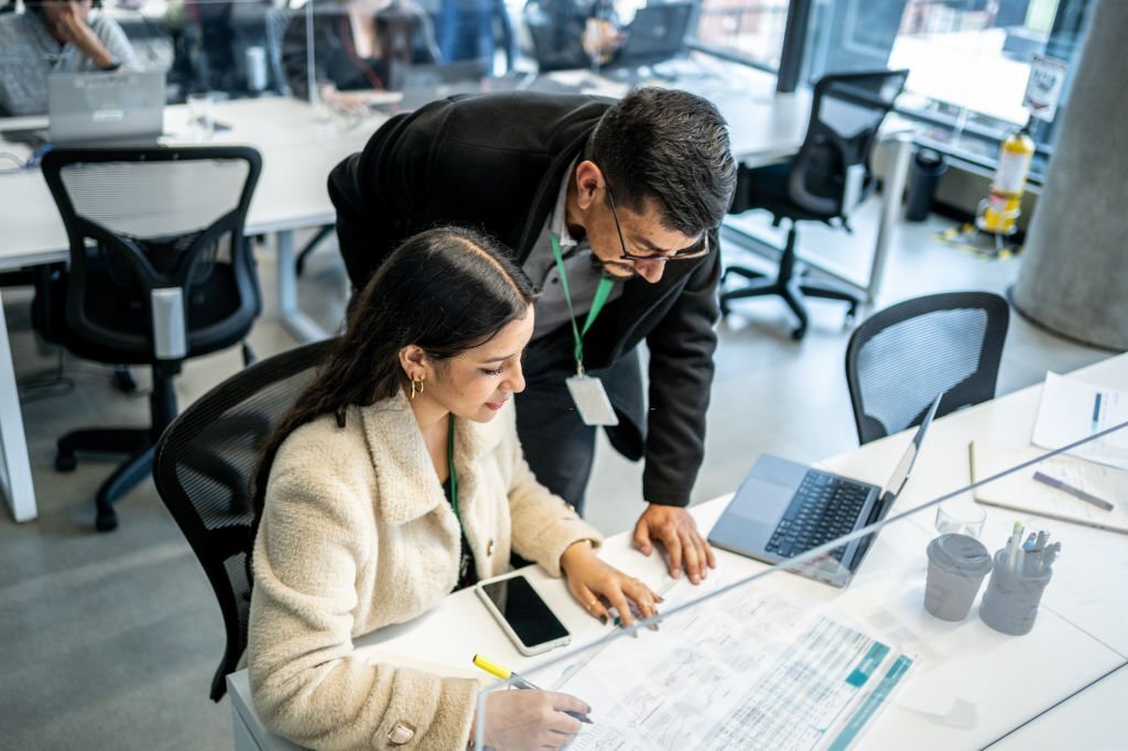 Leader businessman helping young woman in the office